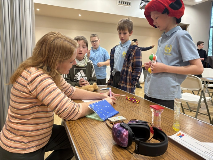 Woman sitting at table with four school boys lined up to see her