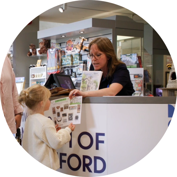 Woman and front desk of Museum of Chelmsford giving activity sheet to little girl