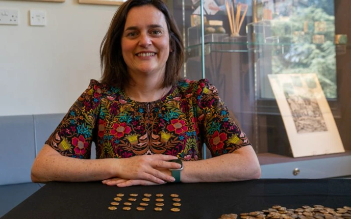 Woman smiling and posing with some coins from Baddow Hoard